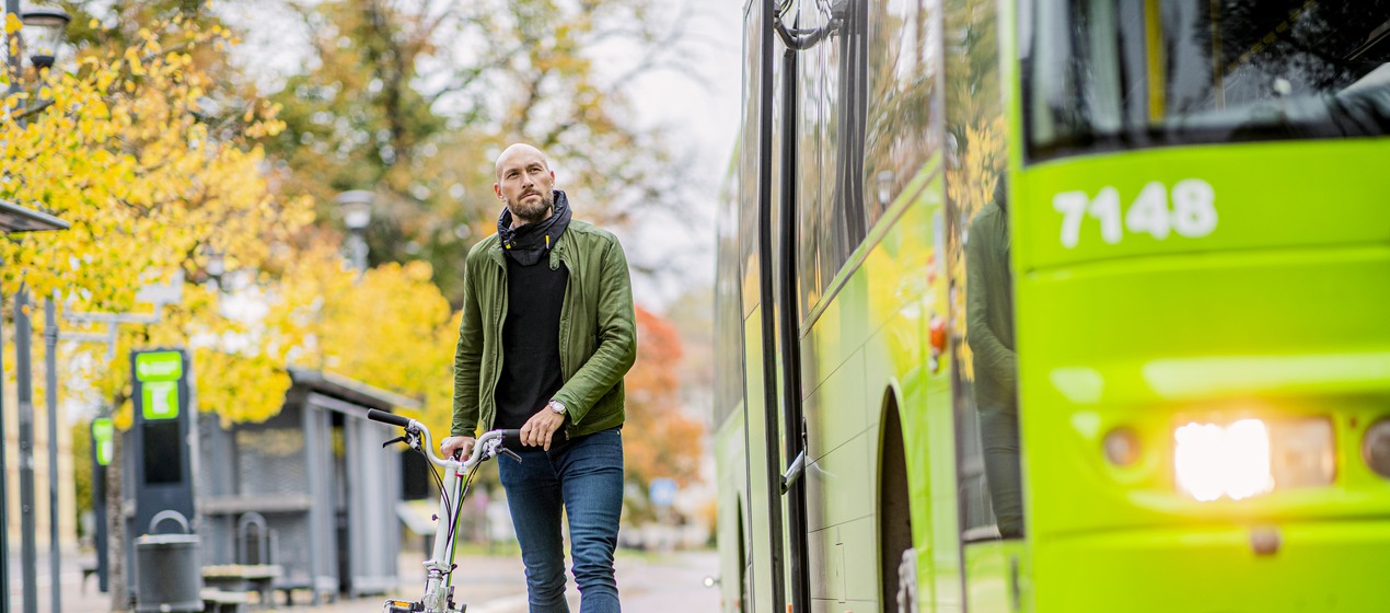 En buss och en man som leder en cykel bredvid bussen